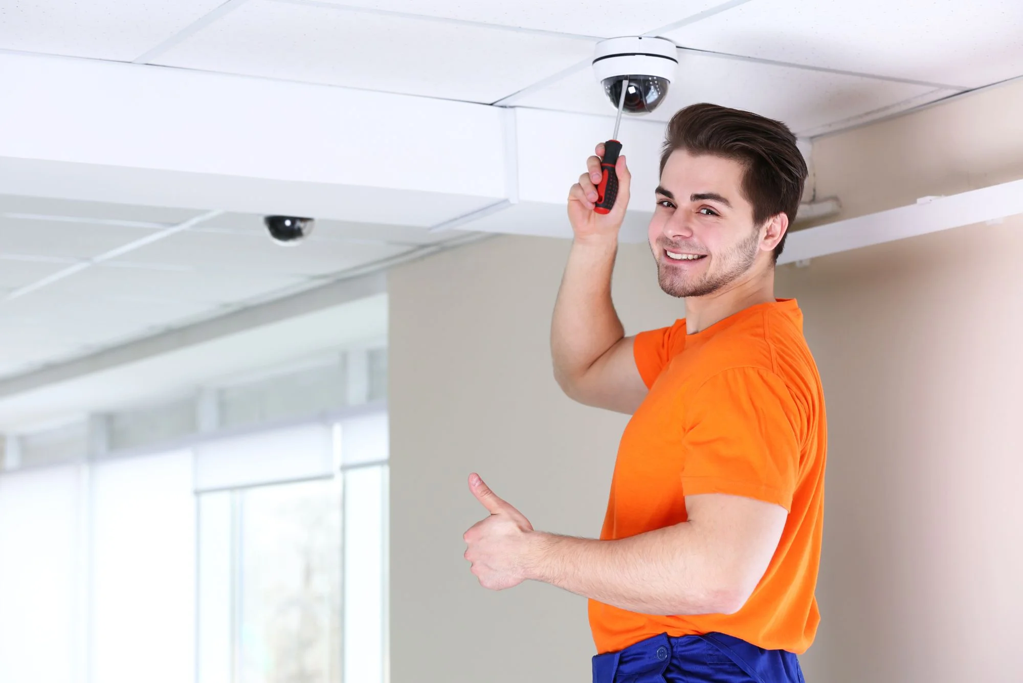 Technician installing a dome camera for commercial security monitoring